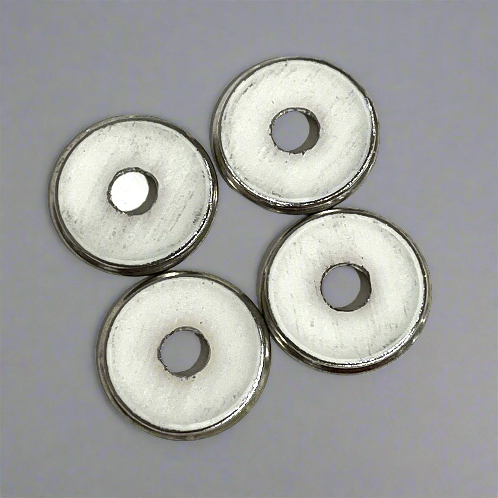 4 flattened shotgun shell slices with plain white undersides showing deprimed center holes, gray background