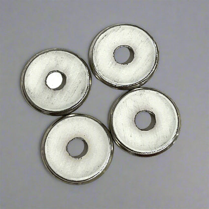 4 flattened shotgun shell slices with plain white undersides showing deprimed center holes, gray background