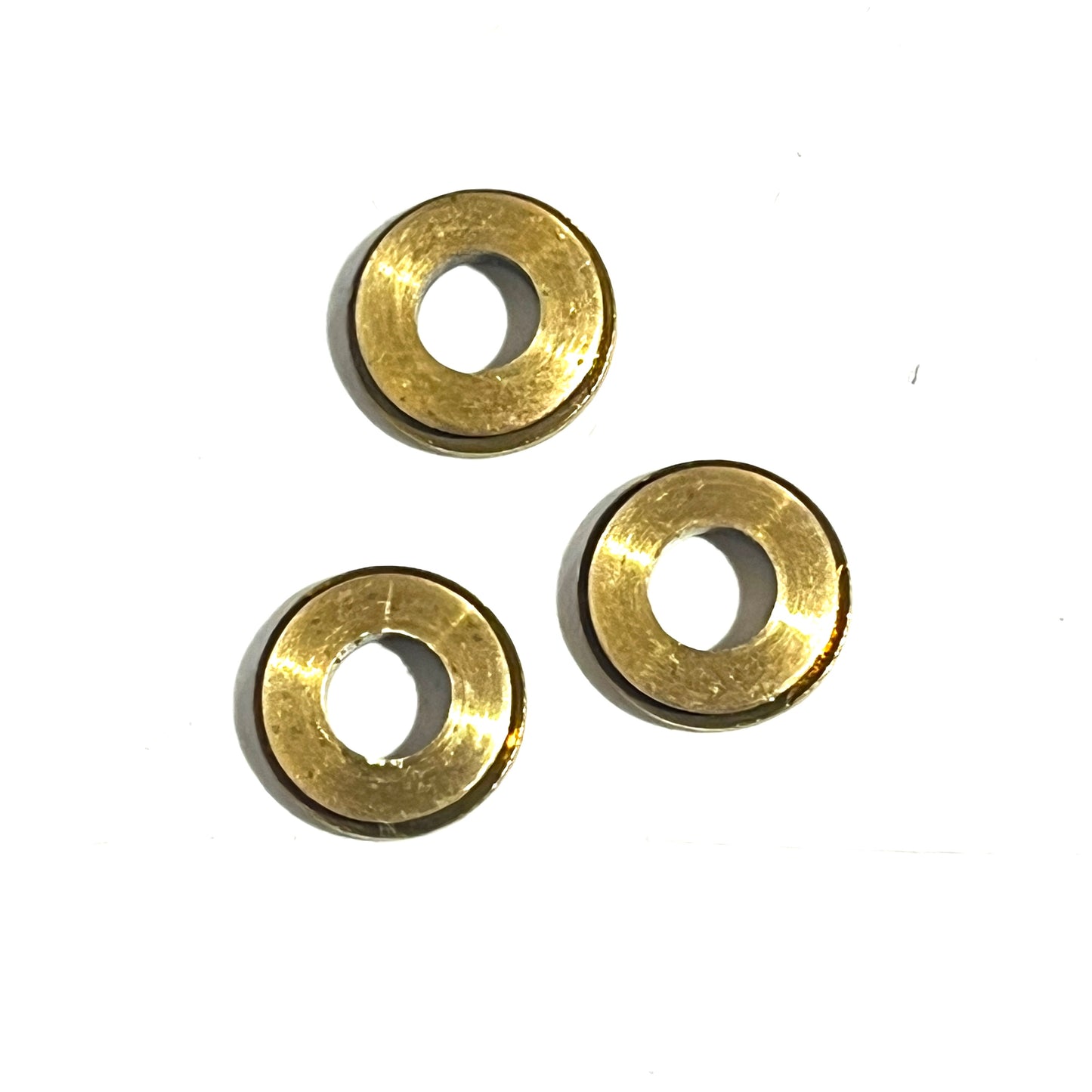 3 gold deprimed bullet slice rings arranged in a triangle on a white background