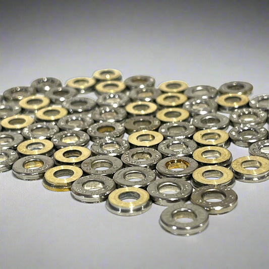 Pile of thin deprimed 380 Auto nickel bullet slices with open primer holes, showing silver finish and brass cut edges.
