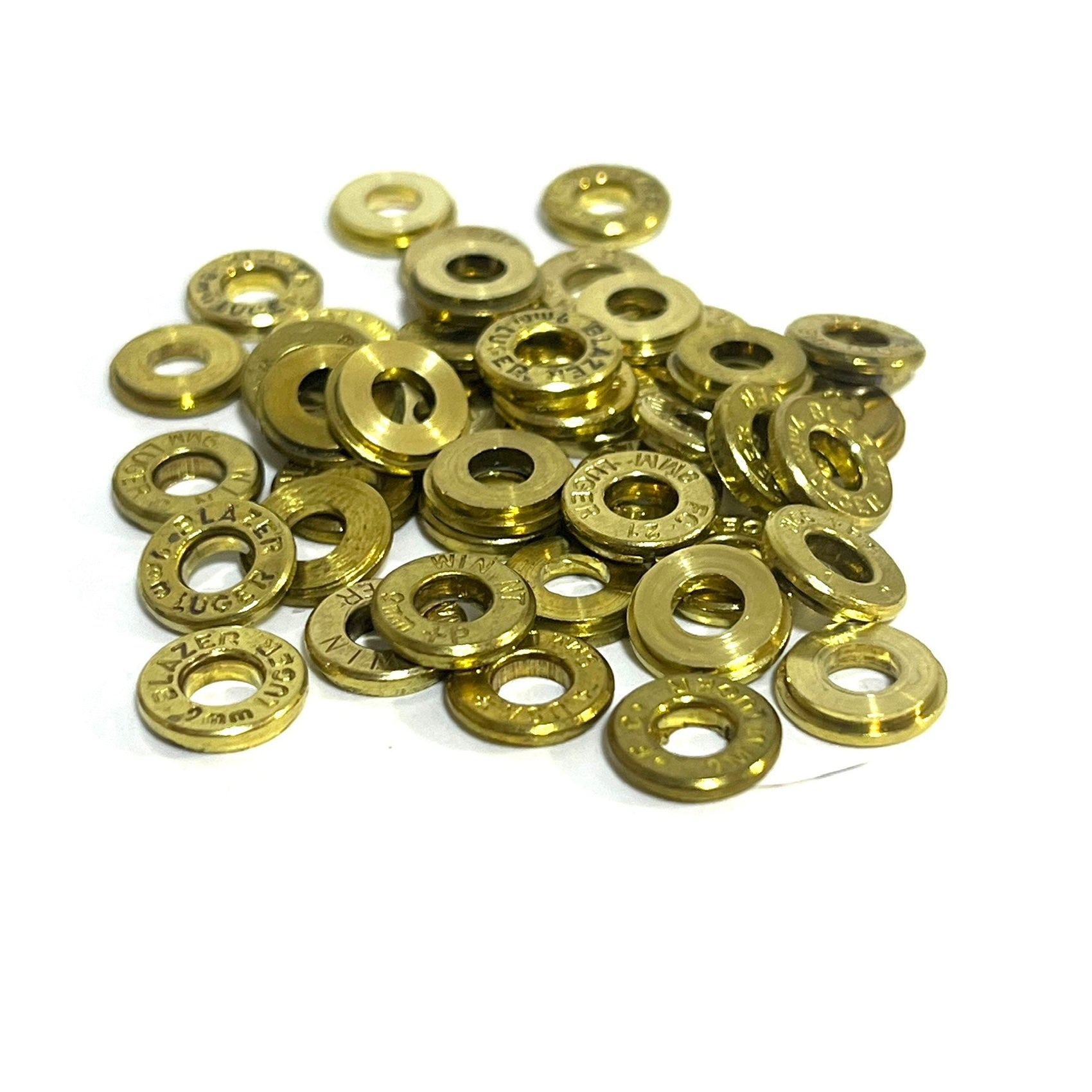A large pile of deprimed 9mm brass slices with primers removed and visible headstamp markings.