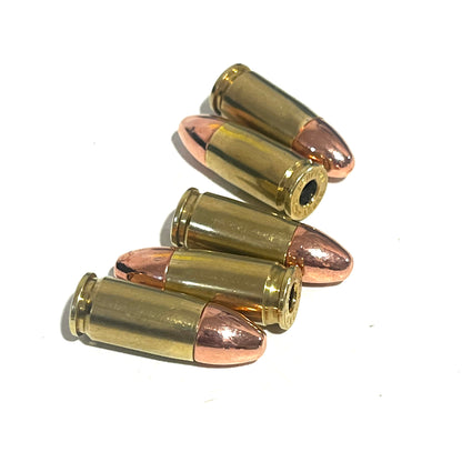 Five deprimed 9mm dummy rounds stacked together on a white background, displaying copper bullets and one empty primer pocket.