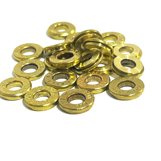 Pile of gold brass deprimed bullet slices from mixed pistol calibers on a white background