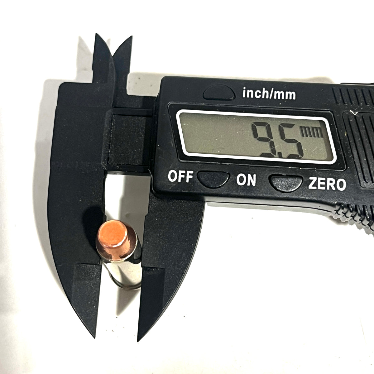Digital caliper measuring the diameter of a copper flat nose bullet at 9.5 millimeters
