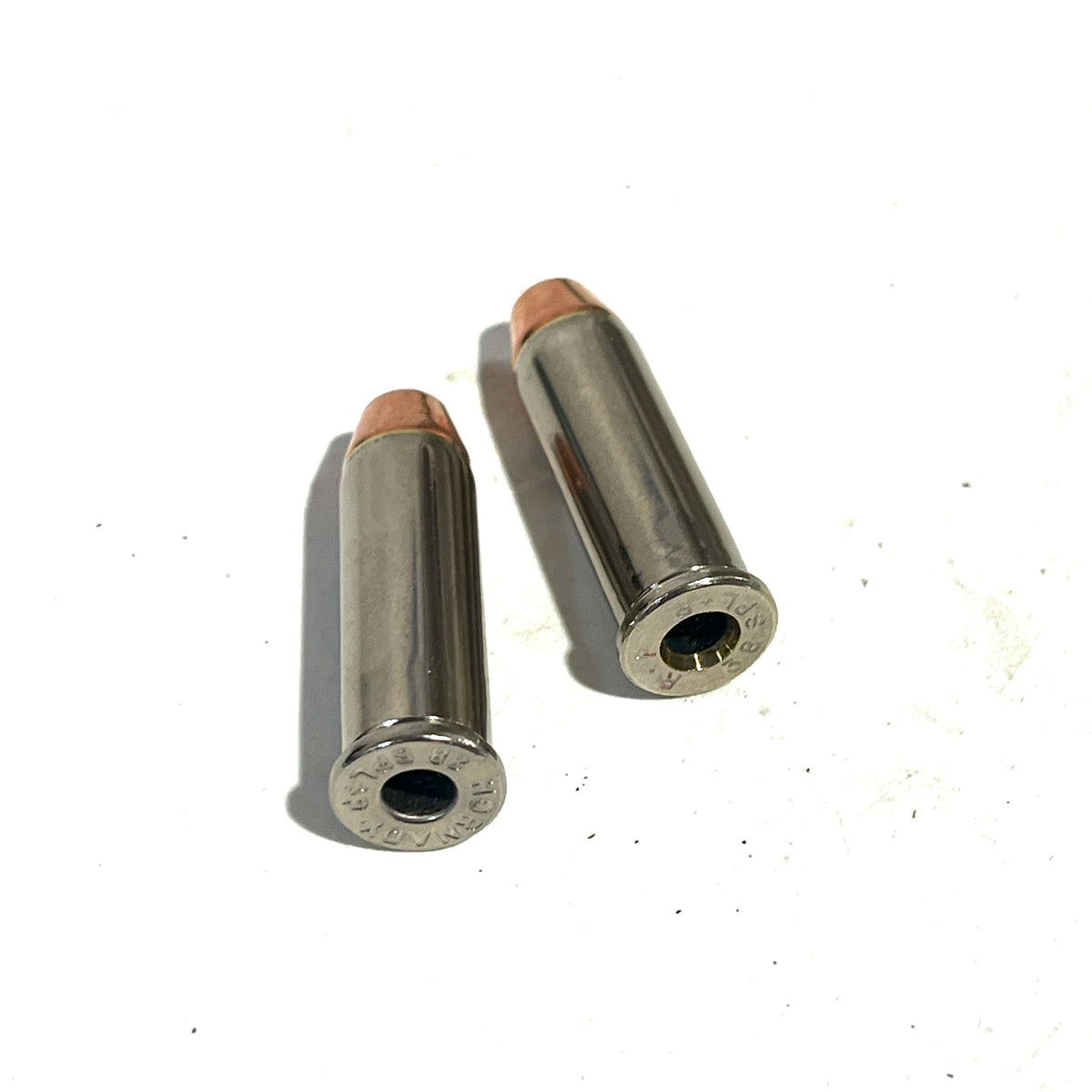 Two deprimed nickel 38 Special dummy rounds with copper flat nose bullets shown from a different angle on a white background.