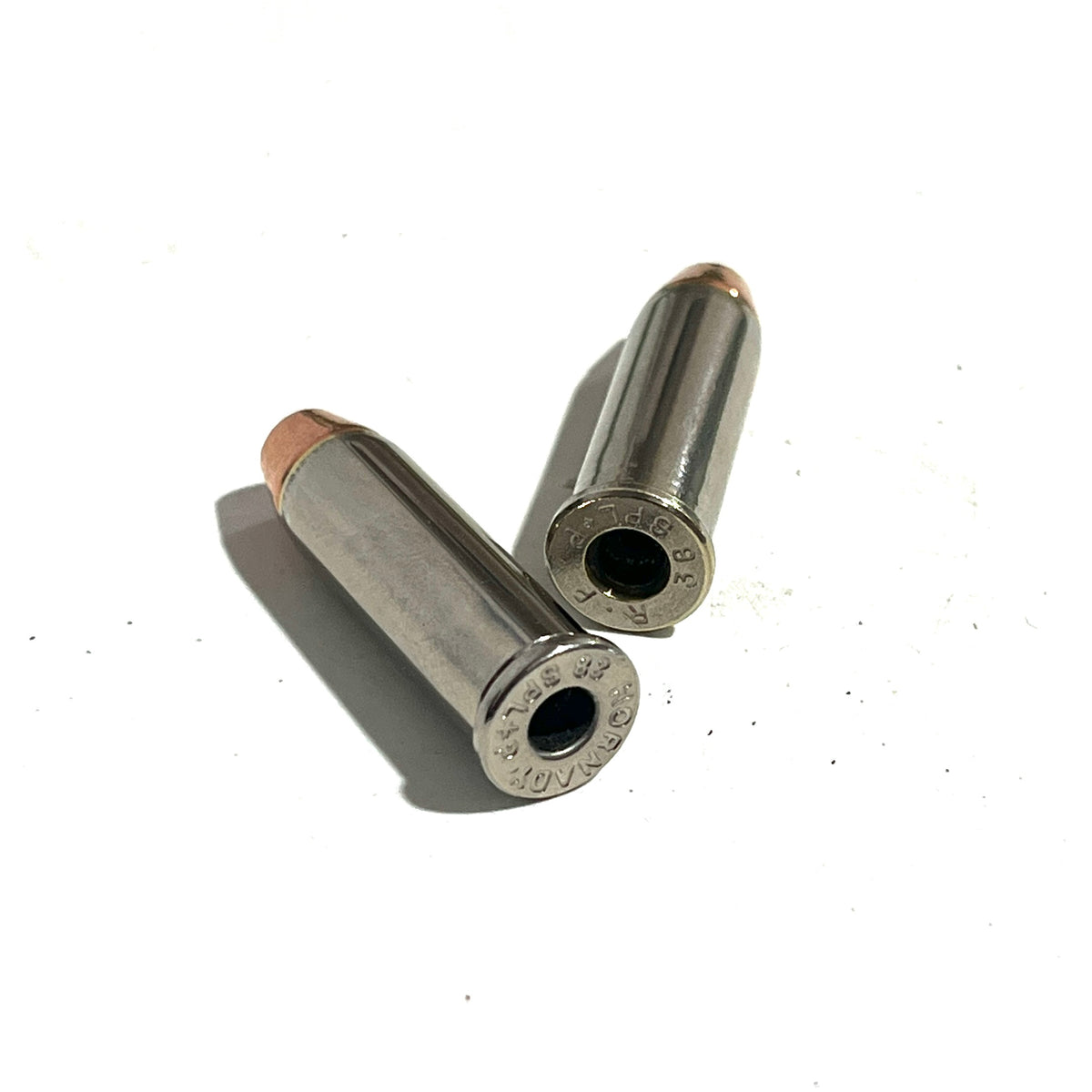 Two deprimed nickel 38 Special dummy rounds with copper flat nose bullets on a white background.
