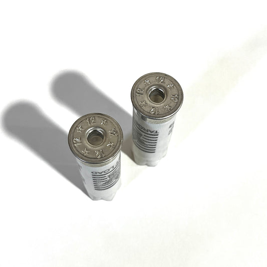 Two deprimed white Stars and Stripes 12 gauge shotgun shells viewed from above showing empty primer holes