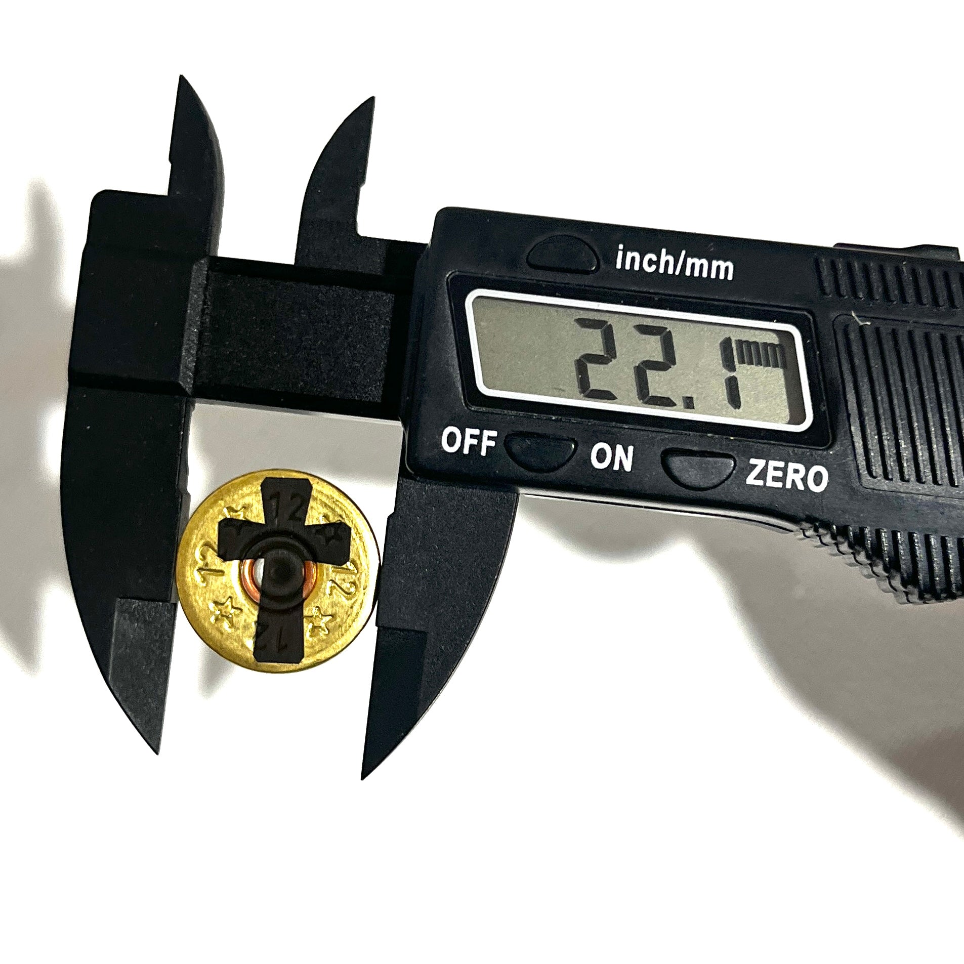 Black digital caliper measuring the 22.1mm diameter of a gold shotgun shell slice featuring a black cross design.
