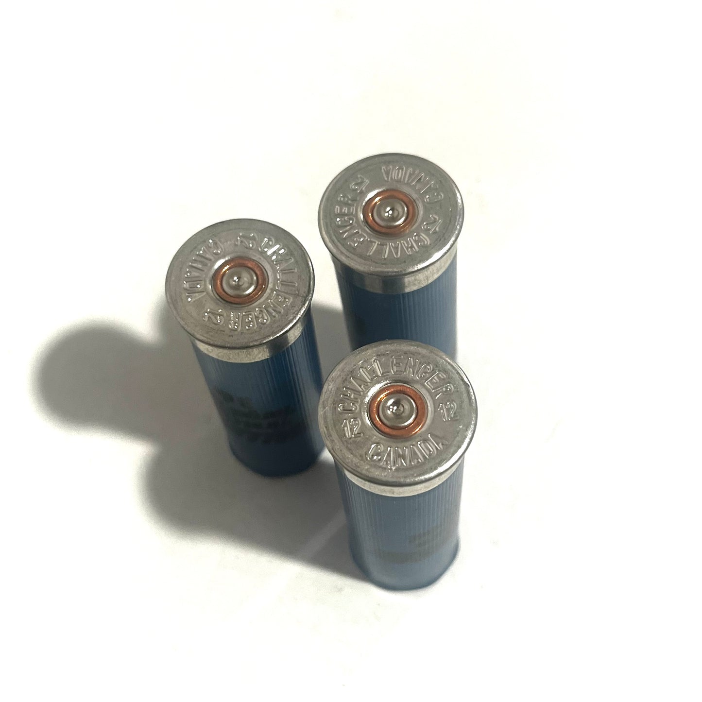 Three blue shotgun shells showing silver Challenger headstamps with copper primers