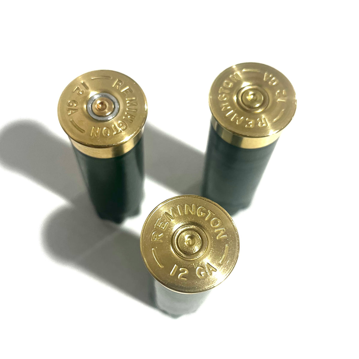 Gold Remington 12 GA headstamps on the bottoms of three emerald green shotgun shells
