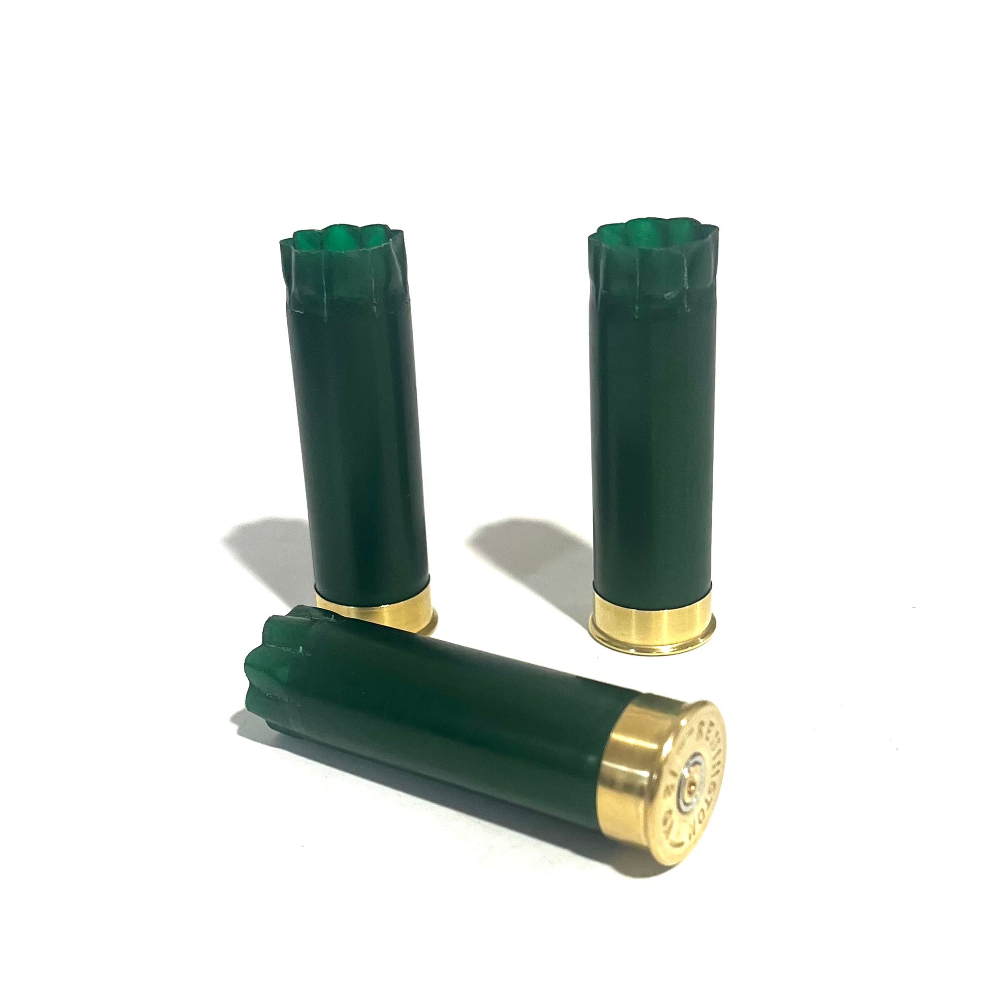Three emerald green shotgun shells with gold bottoms with one lying on its side showing the primer