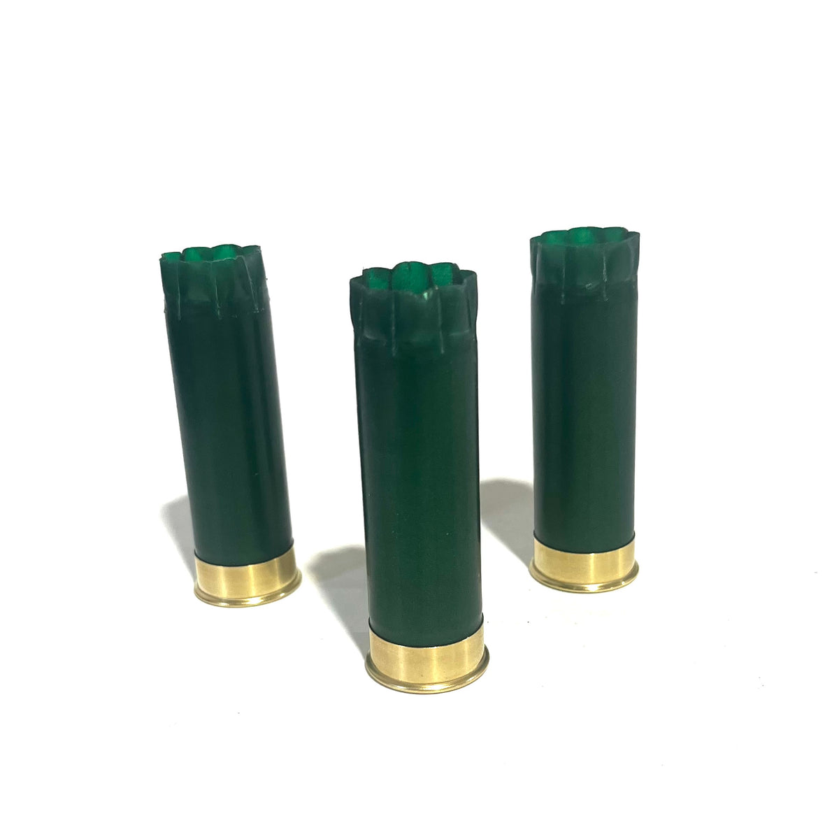 Three emerald green shotgun shells with gold bottoms standing upright showing fluted crimped tops