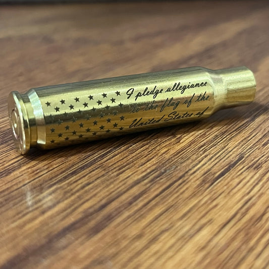 Engraved brass 308 WIN spent casing with stars and script text lying on a wood table