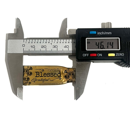 Digital caliper measuring an engraved flattened .308 brass casing at 46.14 millimeters long