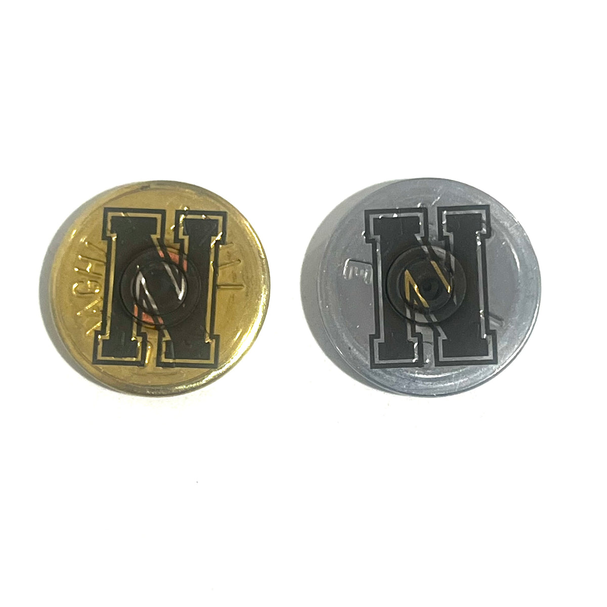 2 round shotgun shell slices, one gold and one silver, each engraved with a bold block letter H, on a white background