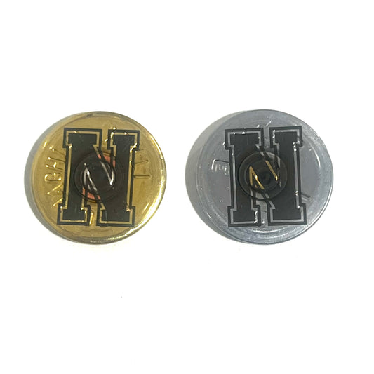 2 round shotgun shell slices, one gold and one silver, each engraved with a bold block letter H, on a white background