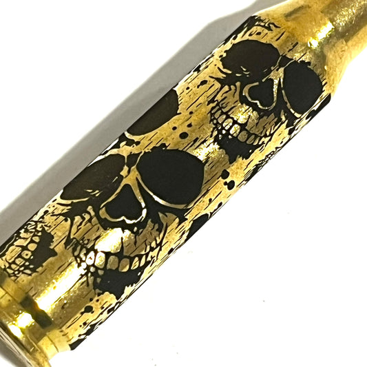Detailed laser-engraved skull pattern across the side of a single 308 WIN brass casing for craft projects.