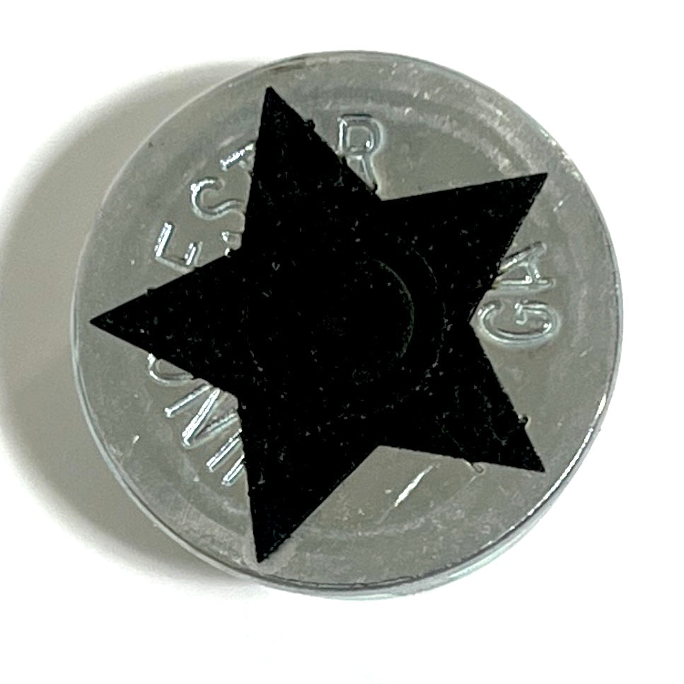 Close-up of a silver 12 gauge shotgun shell slice with a black engraved star design