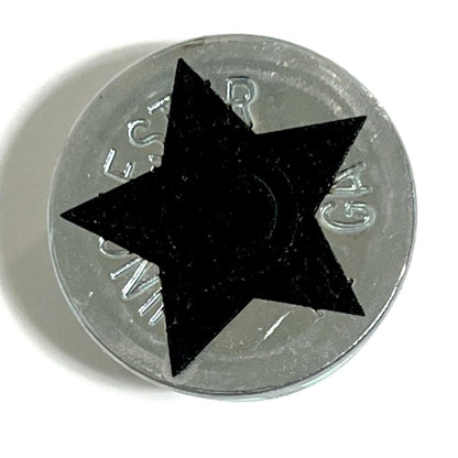 Close-up of a silver 12 gauge shotgun shell slice with a black engraved star design