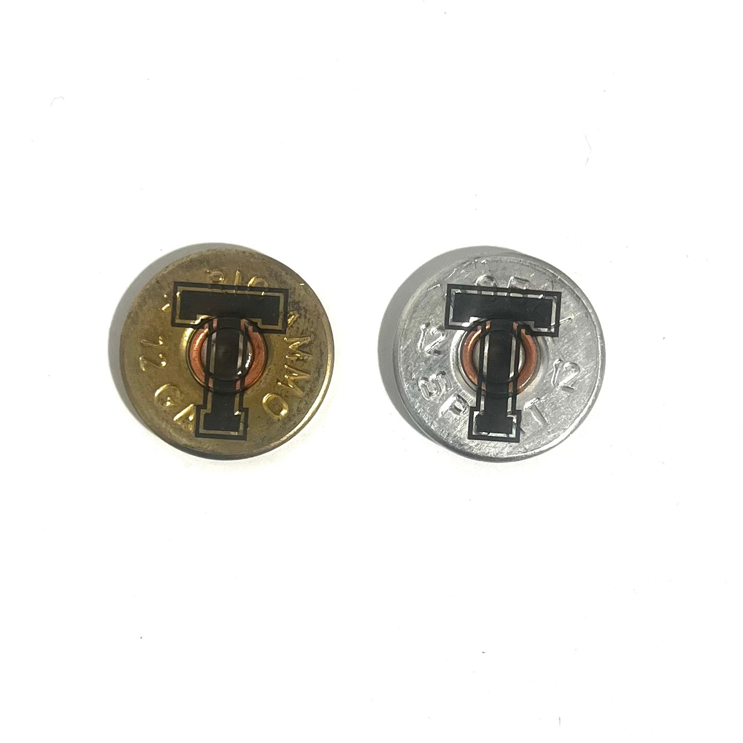 2 round 12 gauge shotgun shell slices engraved with a large letter T, one gold brass and one silver, on a white background