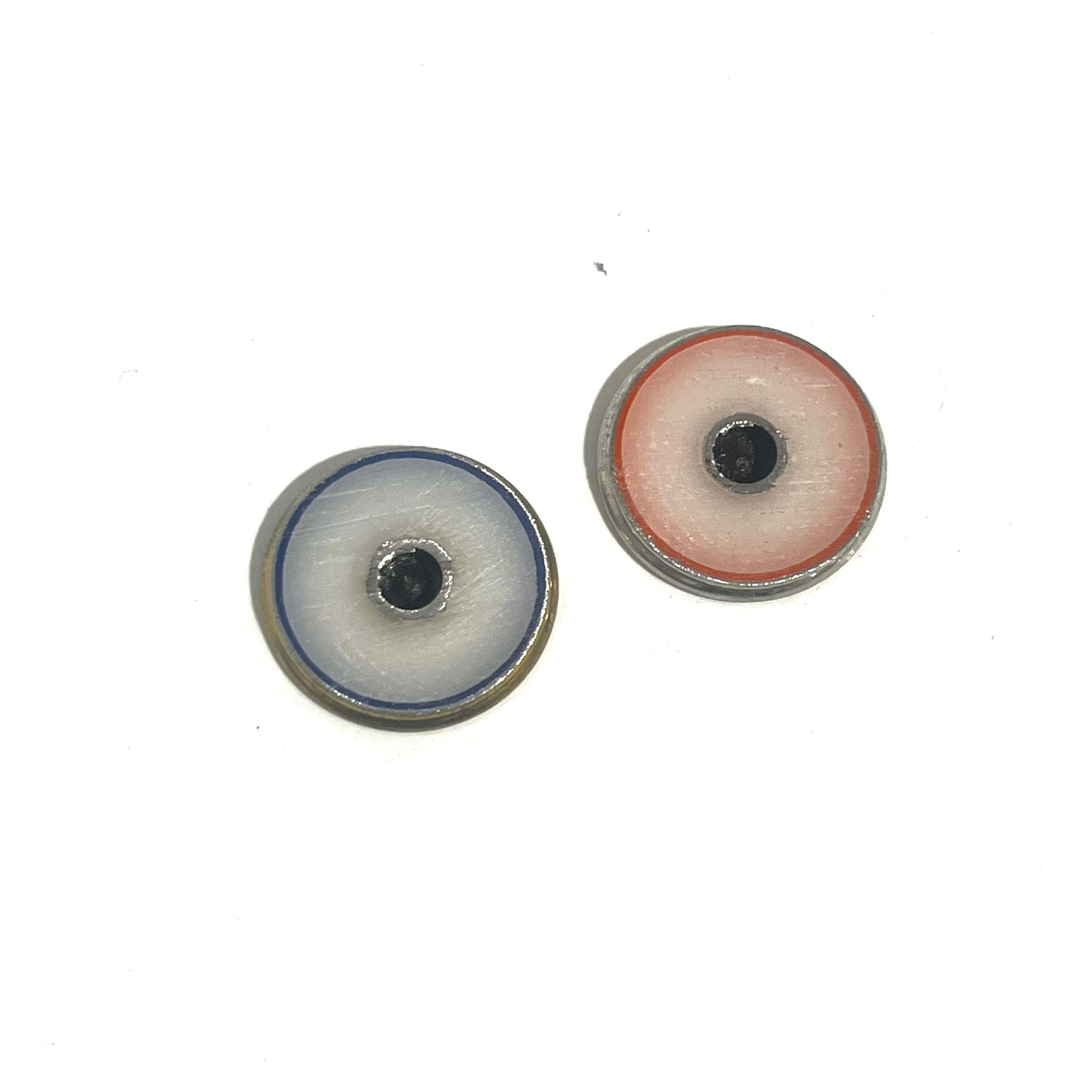 2 round shotgun shell slices viewed from the underside showing white enamel-lined centers with blue and red edging