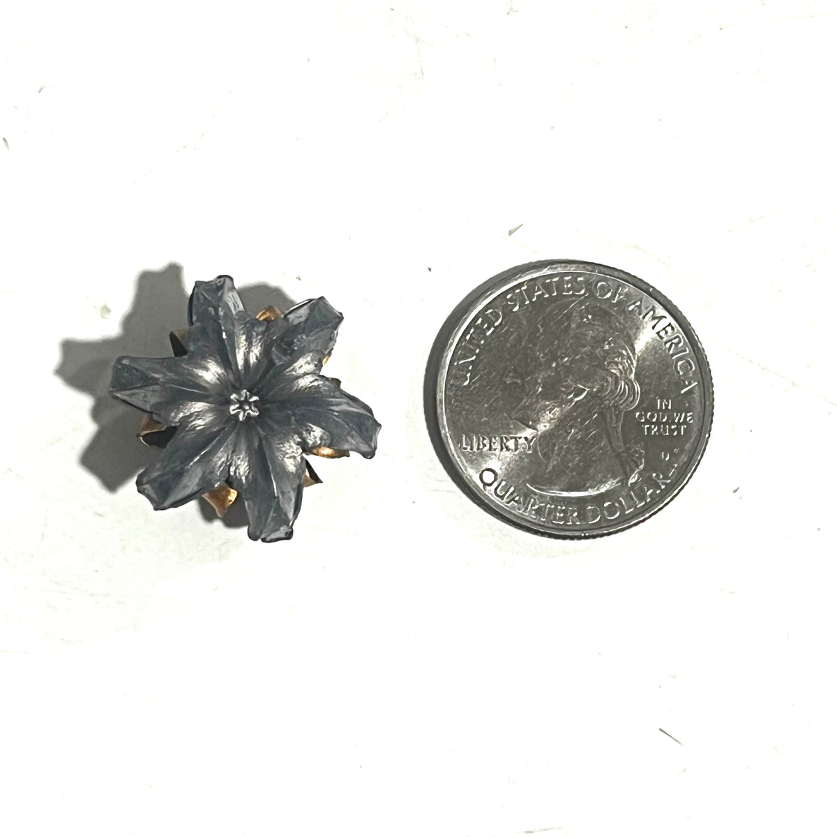 Single .45 ACP expanded hollow point bullet blossom flower charm shown next to a US quarter for size reference