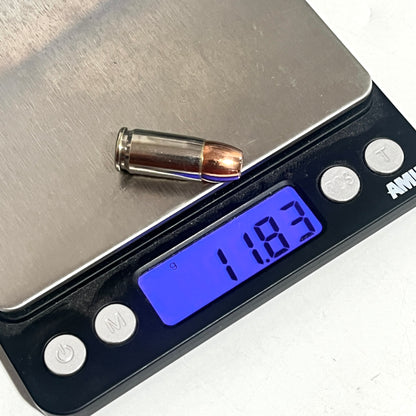 9mm hollow point dummy round fake bullet rests on the metal platform of a digital scale, with the display showing 11.83 grams.