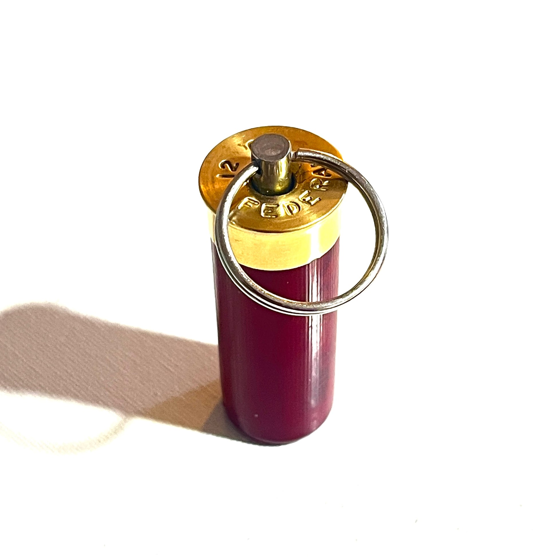 Macro detail of Federal 12 gauge shotgun shell brass headstamp, stainless steel swivel, and nickel-free split ring.
