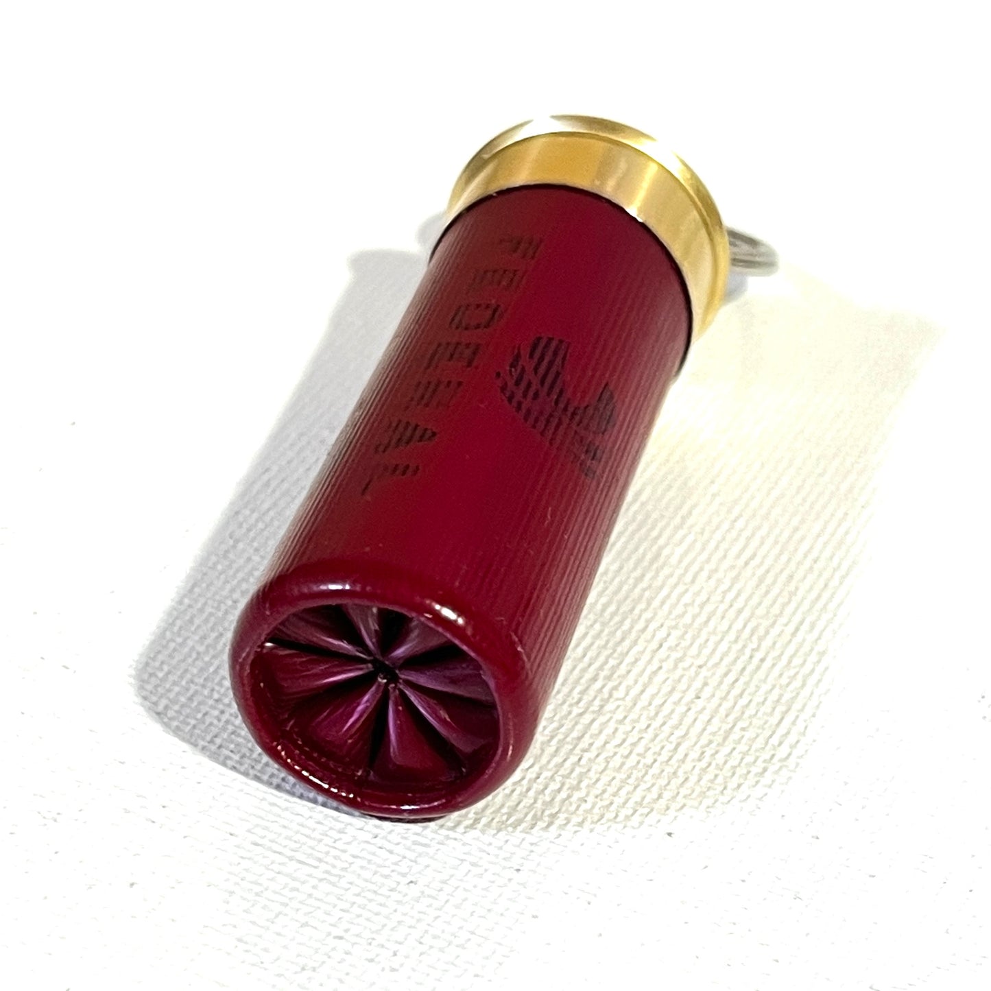 Detail of the red plastic hull texture, black Federal branding, and crimped end of a 12 gauge shotgun shell keychain.
