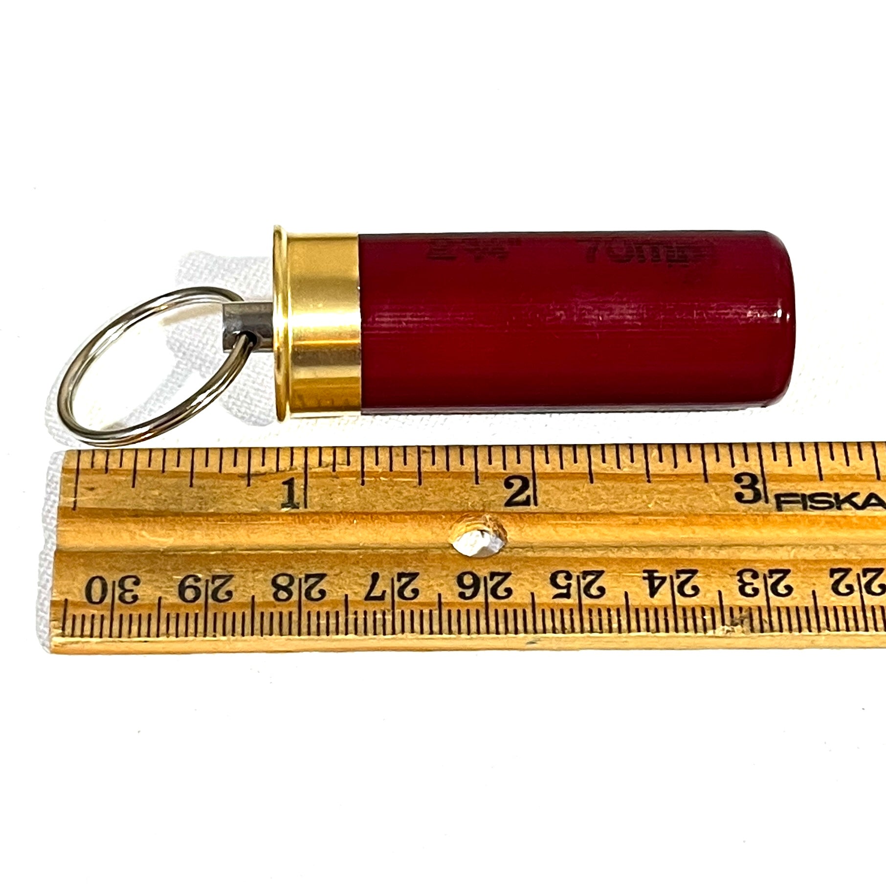 12 gauge shotgun shell keychain shown next to a ruler to demonstrate its 3-inch length for EDC gear scale.
