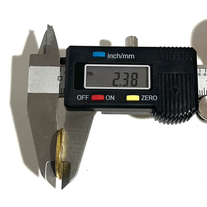 Digital caliper measuring a brass 12 gauge shotgun shell slice at 2.38 mm thick