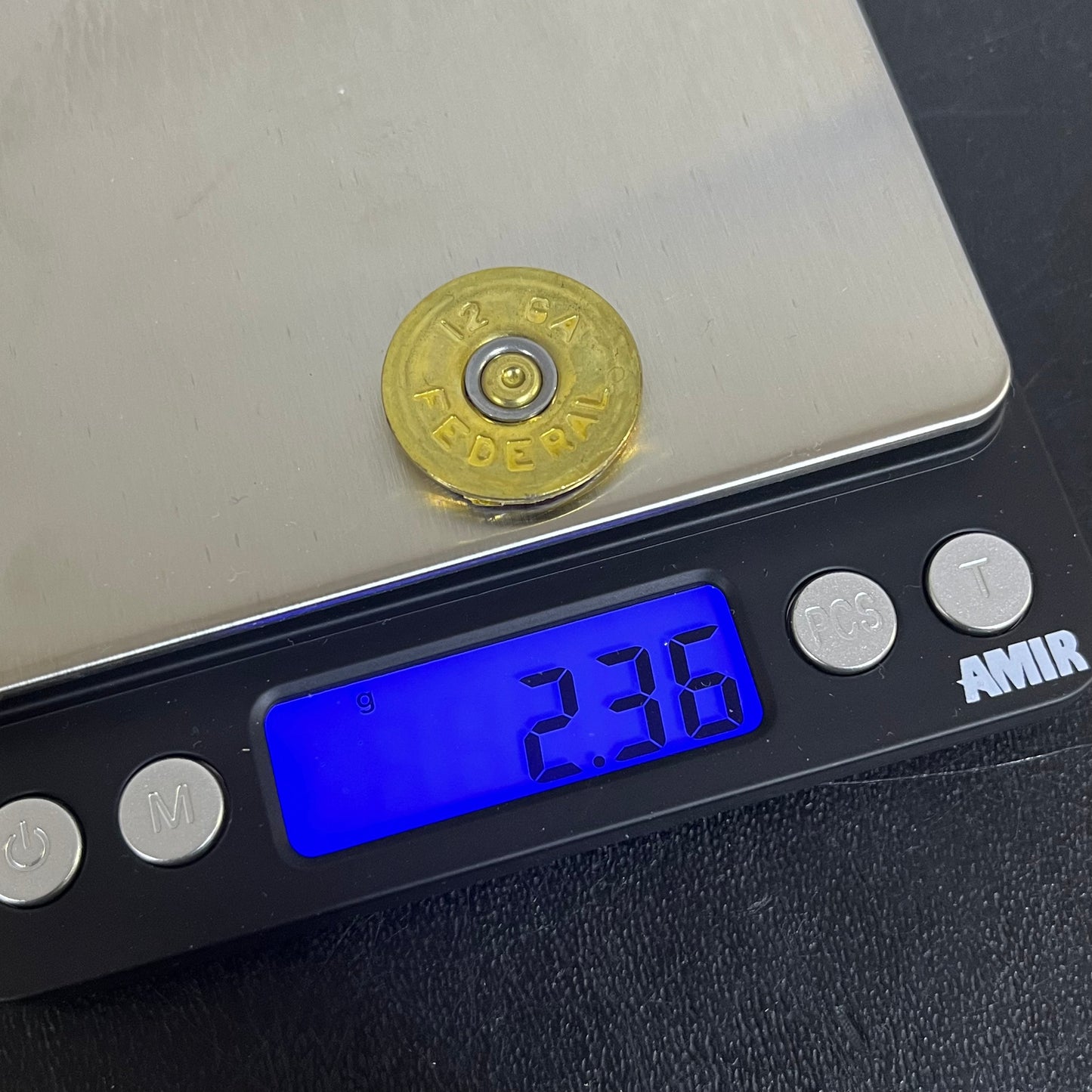 Round brass 12 gauge Federal headstamp slice on a digital scale reading 2.36 grams