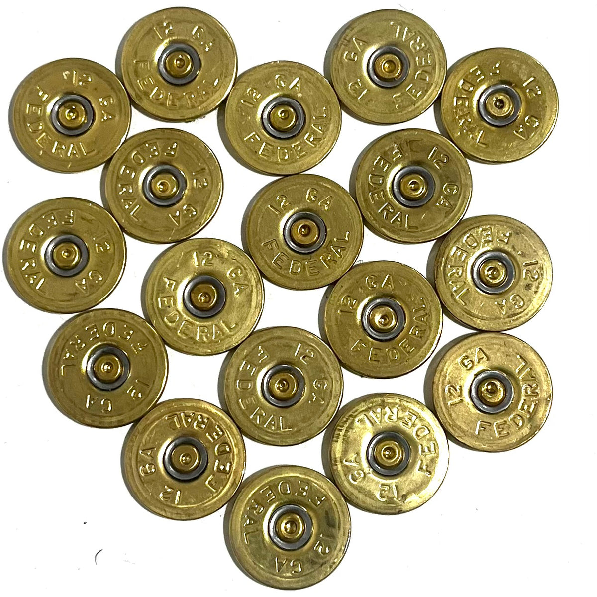 18 round brass 12 gauge Federal headstamp slices arranged in a cluster on a white background