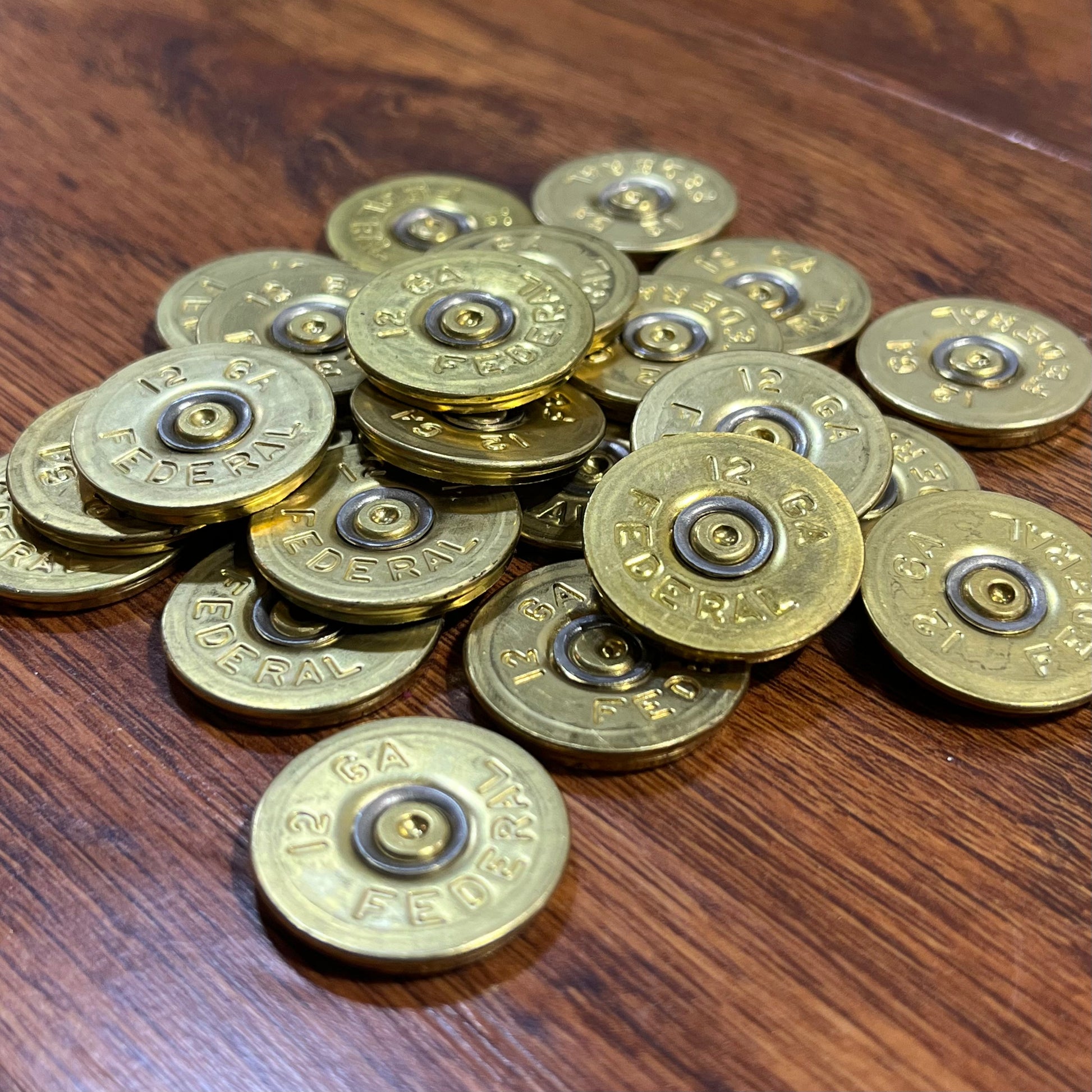 Pile of round brass 12 gauge Federal headstamp slices on a wood surface