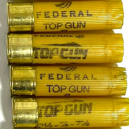 Federal 20 gauge empty shotgun shells, yellow plastic hulls laid horizontally for DIY rustic boutonniere projects.
