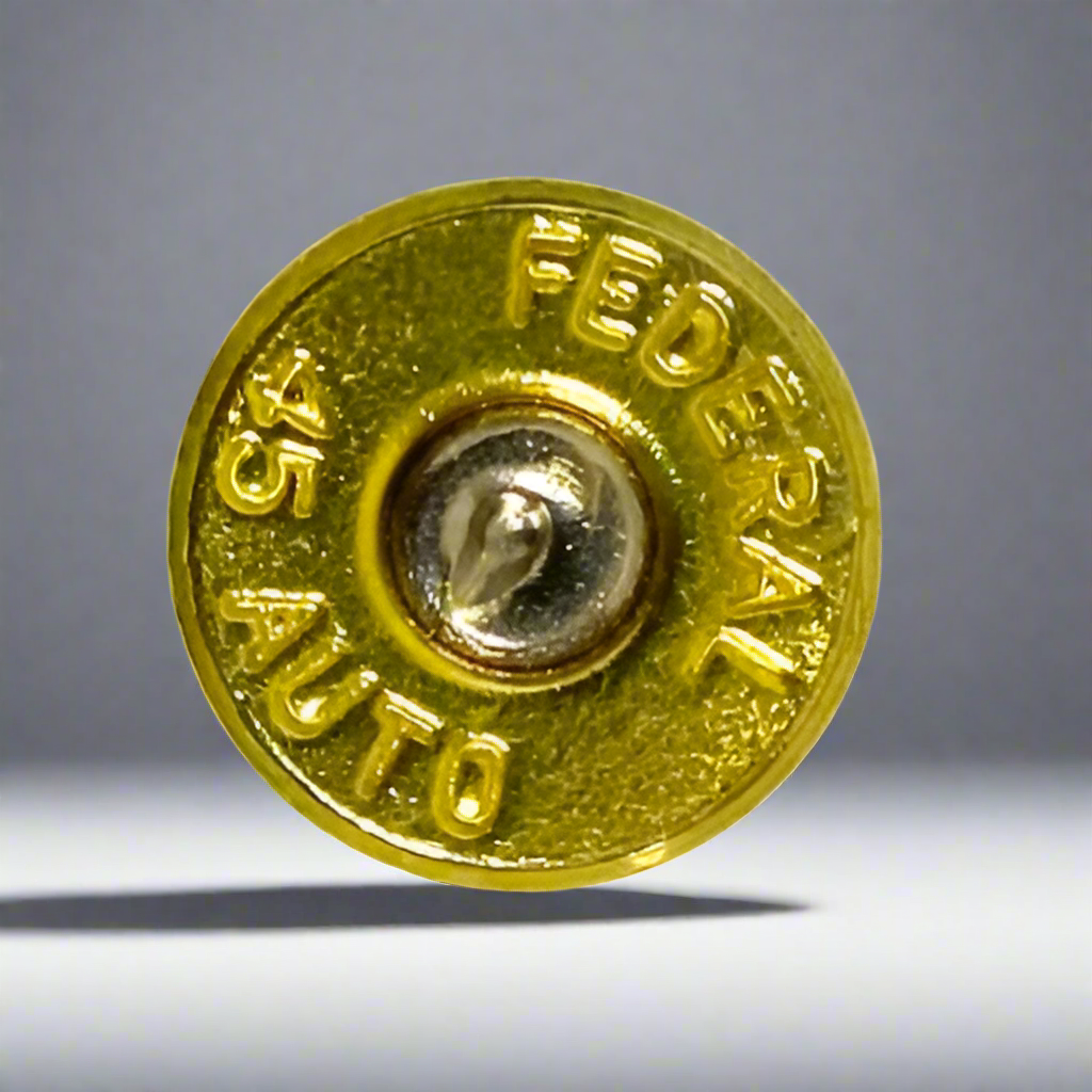 Gold Federal 45 ACP brass slice standing upright with headstamp visible against a gray gradient background.