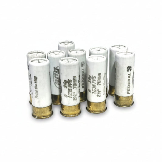Eight white empty Federal Gold Medal 12 gauge dummy rounds standing upright with open tops, gold brass bases, and Federal markings on a white background.
