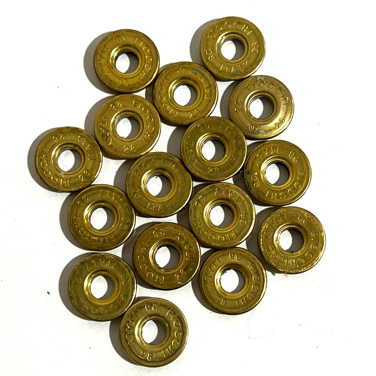 15 gold brass Fiocchi 28 gauge shotgun shell slices arranged in a cluster on a white background