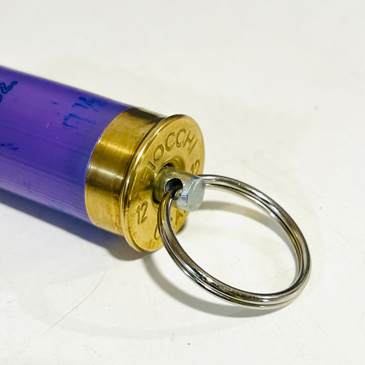 Close-up of the Fiocchi 12 gauge brass head with stainless swivel pin and nickel-free split ring on a lavender shell keychain