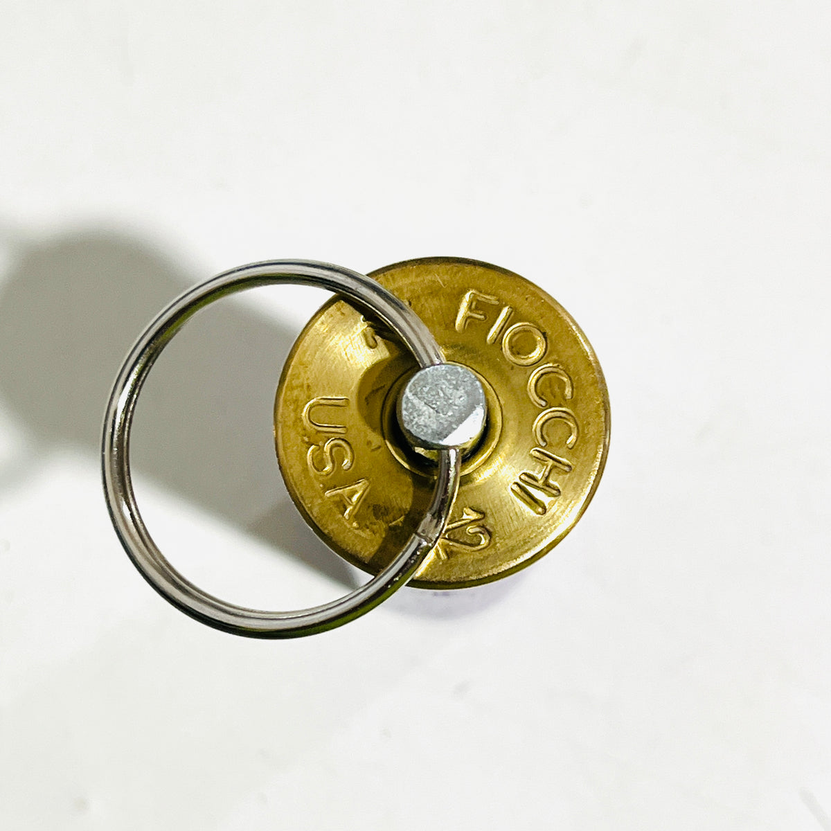 FIOCCHI 12 USA headstamp on a spent lavender shotgun shell keychain, stainless swivel pin through the primer pocket and steel split ring