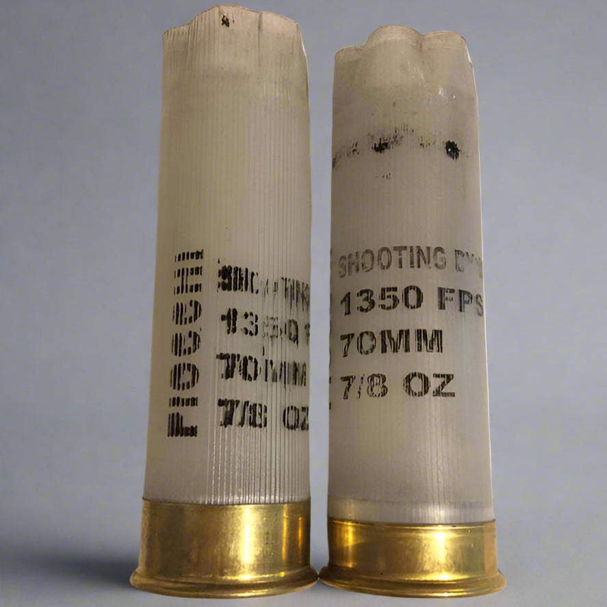 Two empty translucent Fiocchi 12ga hulls with brass bases showing scorch marks and stamped text
