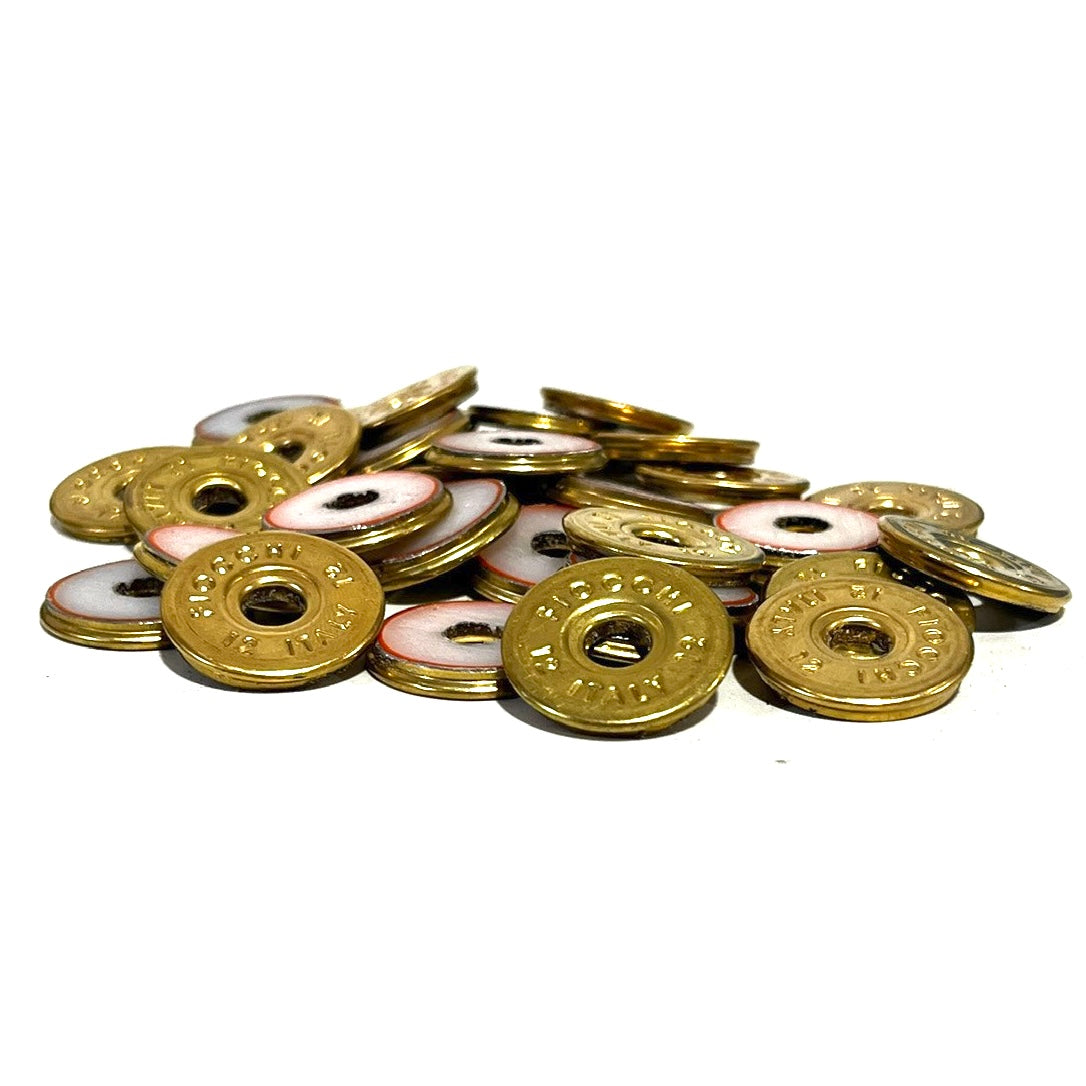 Pile of round brass 12 gauge Fiocchi Italy deprimed slices with white and red enamel-lined centers on a white background