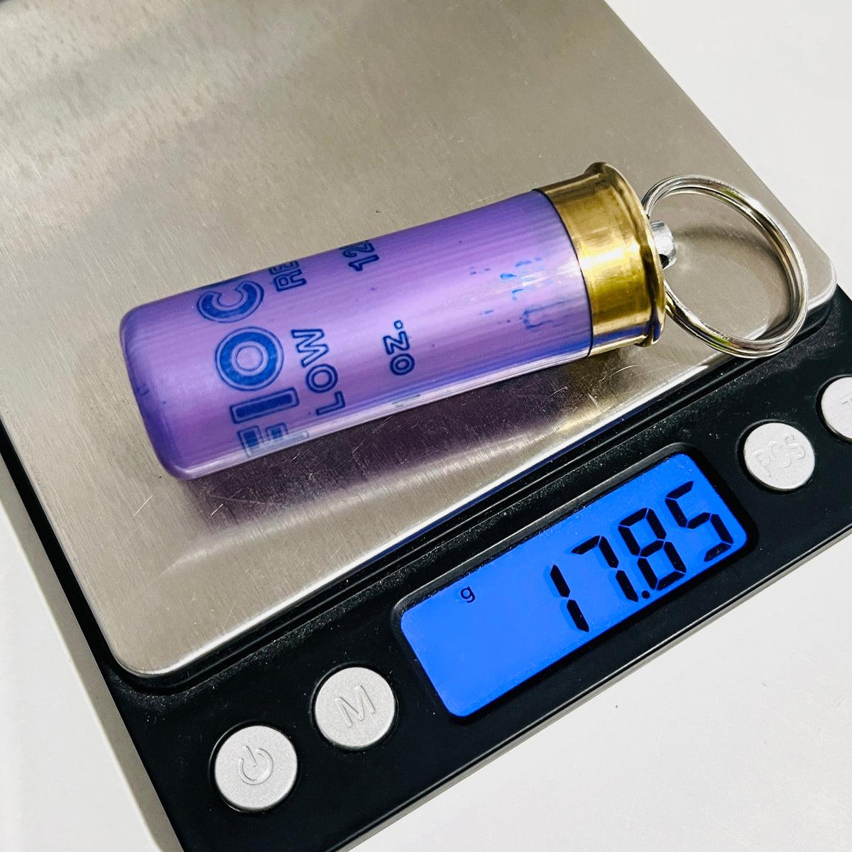 Lavender Fiocchi 12 gauge shotgun shell keychain on a digital scale reading 17.85 g