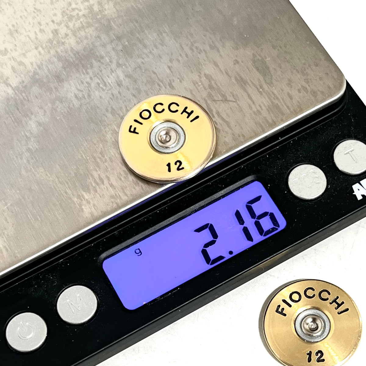 Digital scale showing a gold Fiocchi 12 gauge shotgun shell slice weighing 2.16 g