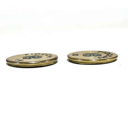 Two gold Fiocchi shotgun shell slices viewed at a low angle showing their thin flat profile