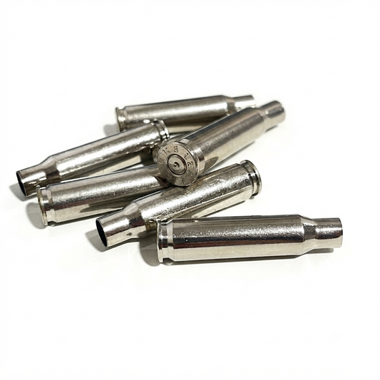 Overlapping group of five silver .308 WIN empty cartridges on a white surface, with the top base displaying a spent primer.
