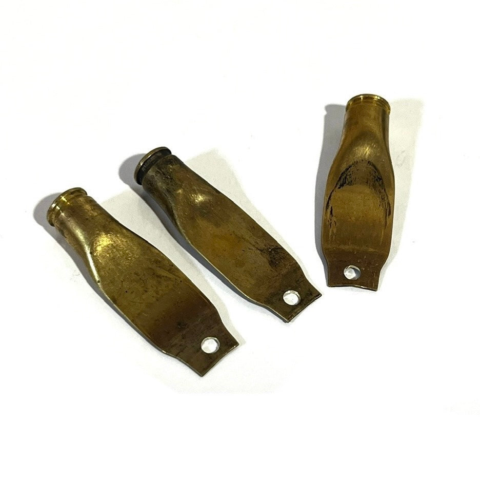 3 flattened brass casings with drilled holes shaped like paddles on a white background