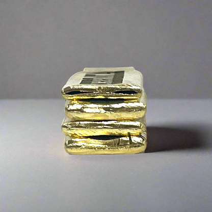 Edge view of stacked flattened .308 brass casing pieces showing their rough-cut handmade finish
