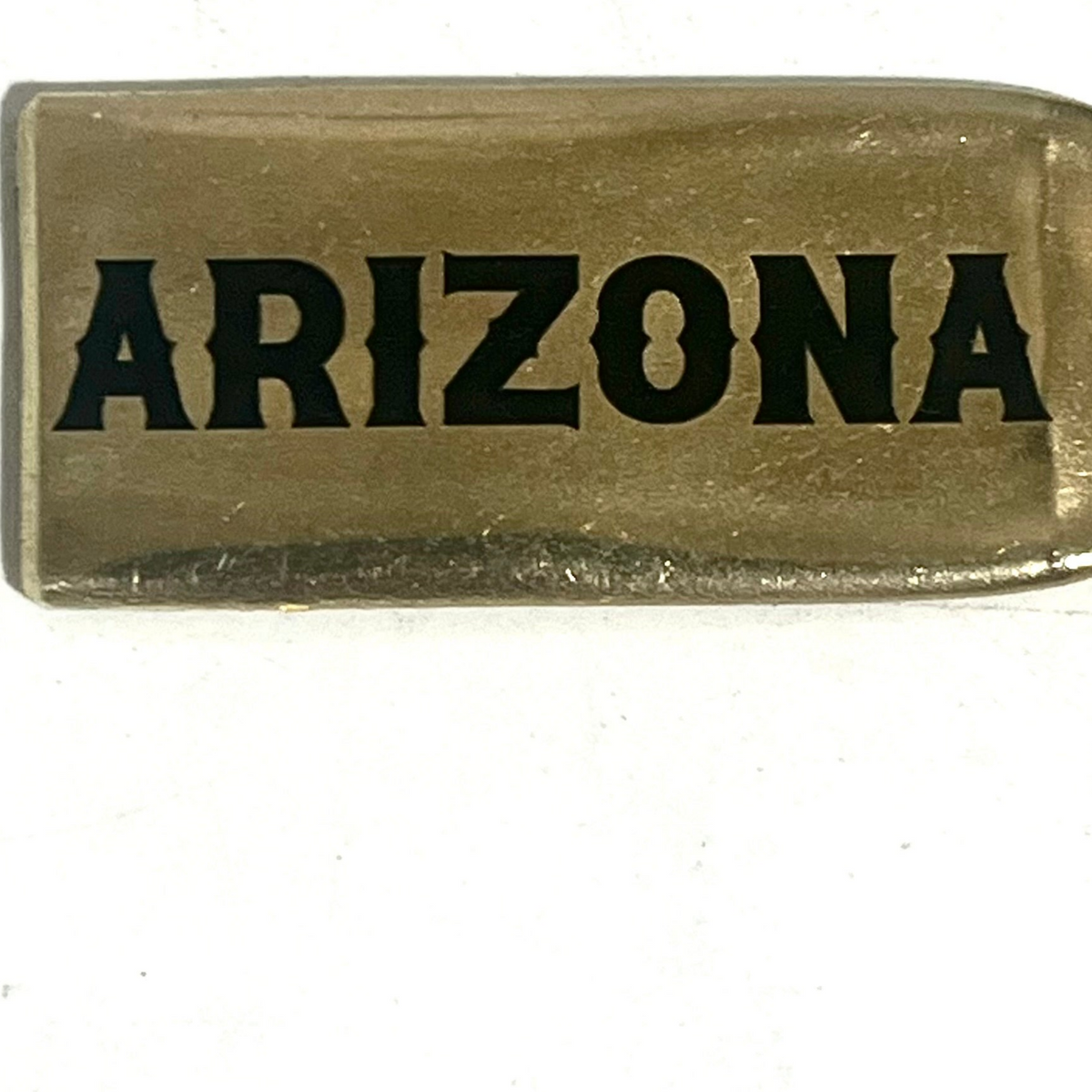 Close-up of a flattened brass .308 casing engraved with Arizona in black lettering