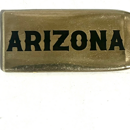Close-up of a flattened brass .308 casing engraved with Arizona in black lettering